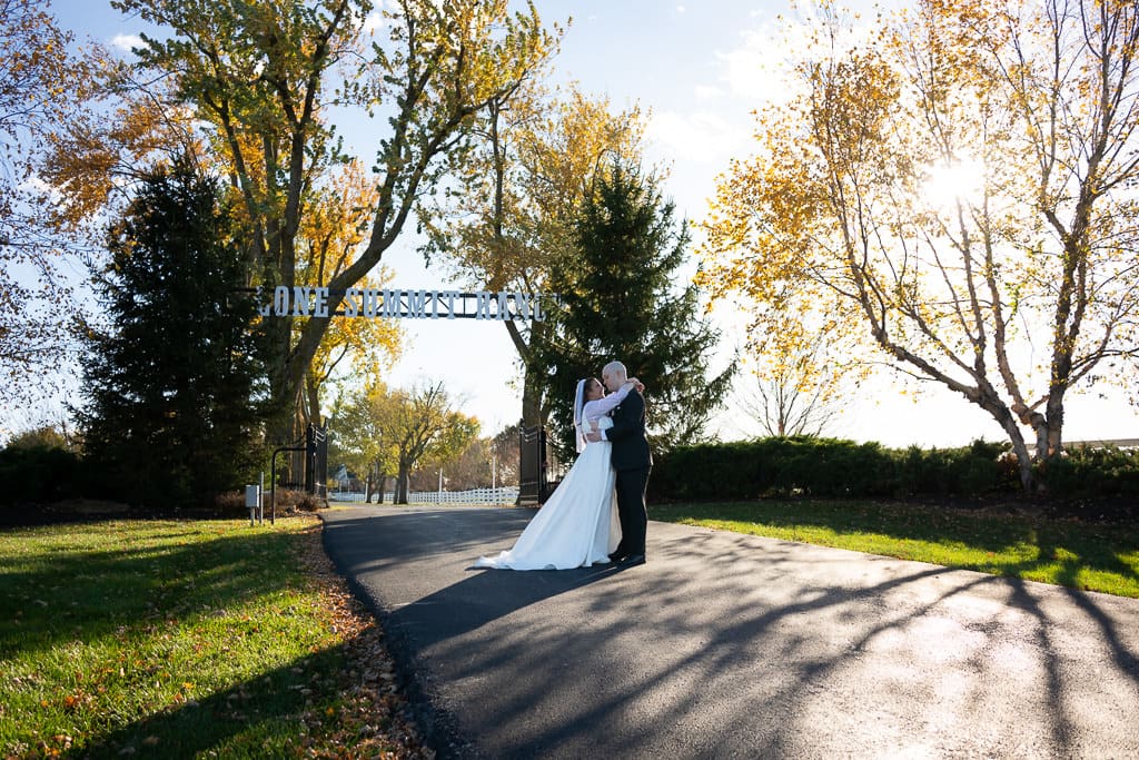 Lone Summit Ranch Wedding venue entrance with couple posing sunny fall day