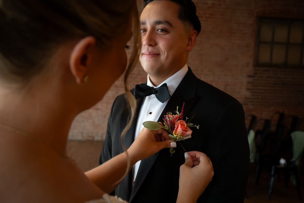 Bride fixing the boutonniere on her groom during a multicultural wedding.