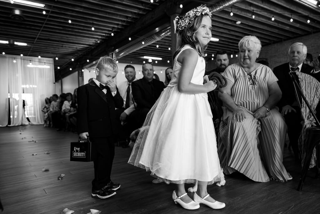 Ring bearer boy carrying a suitcase and flower girl walking down the aisle at Union KC