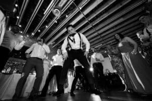 Groom dancing in the air, photographed from below, with the ceiling of Union Kansas City in the background