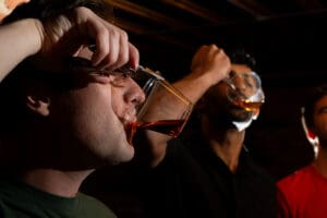 Groomsmen using multitool gifts to grab and drink from their whiskey glasses, with dramatic light highlighting their faces and glasses