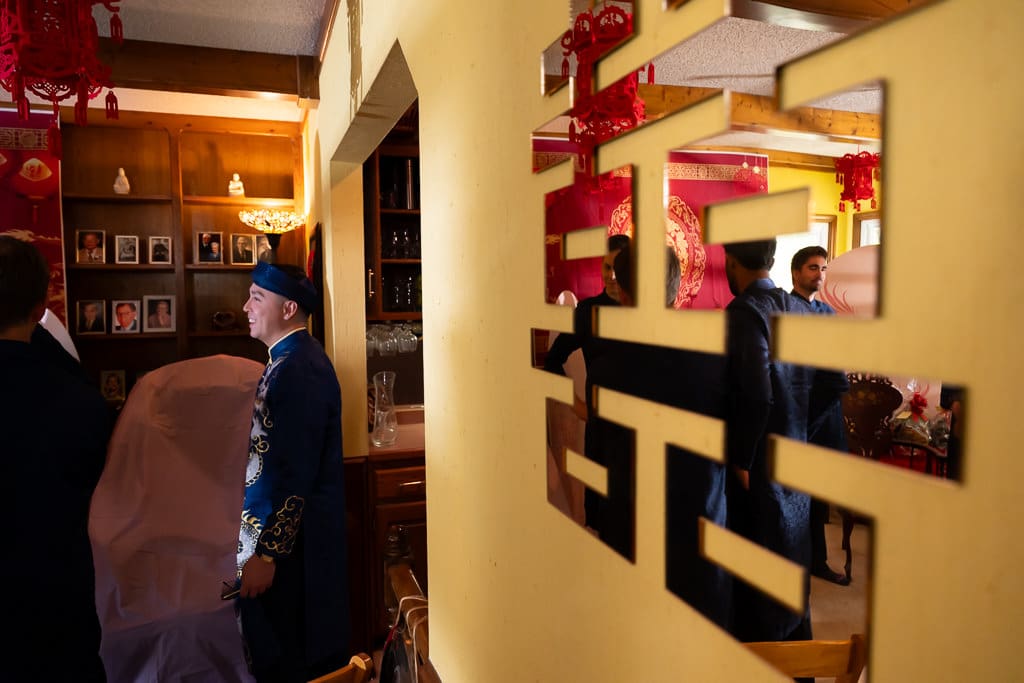 Groom standing next to mirror with Chinese characters