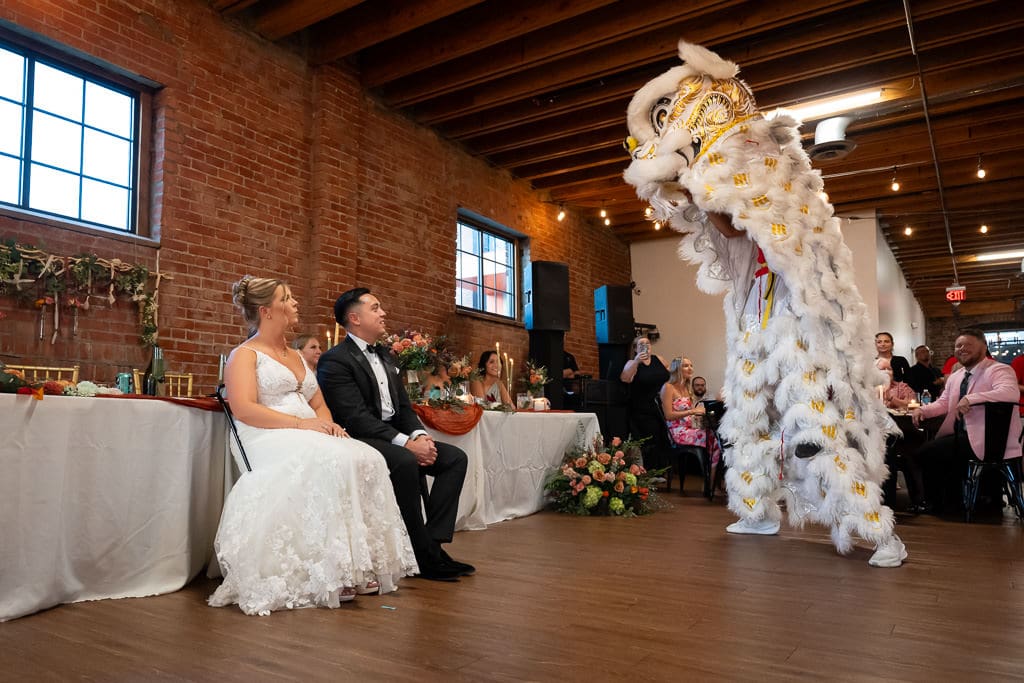 Lion dancer standing up next to the couple during a Vietnamese multicultural wedding at Union Kansas City
