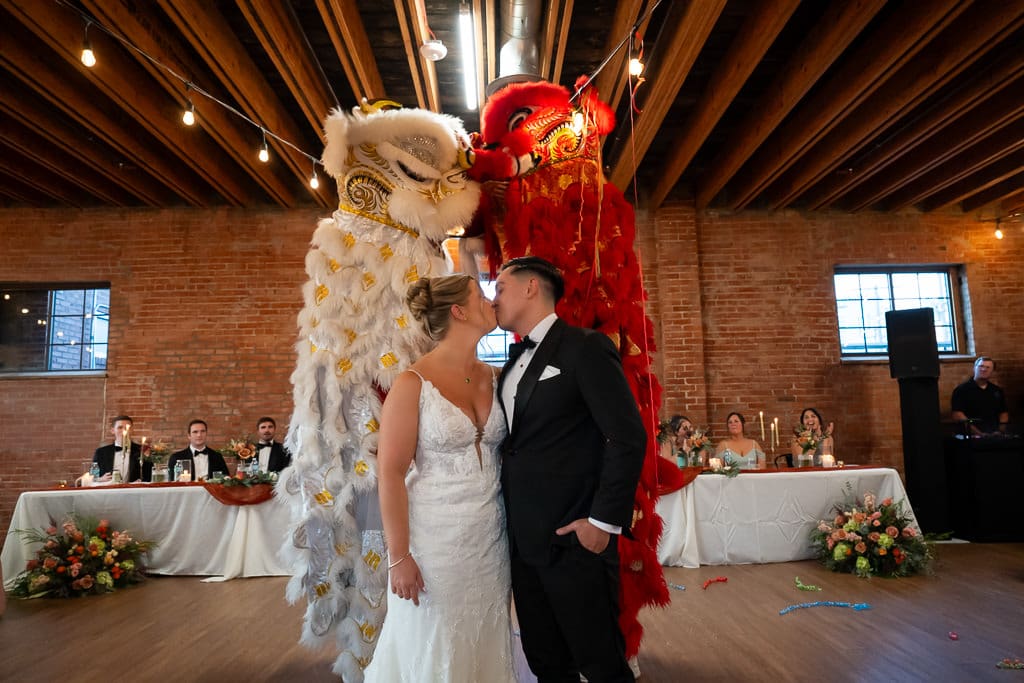 Couple kissing in front of two lion dancers during a Vietnamese multicultural wedding at Union Kansas City