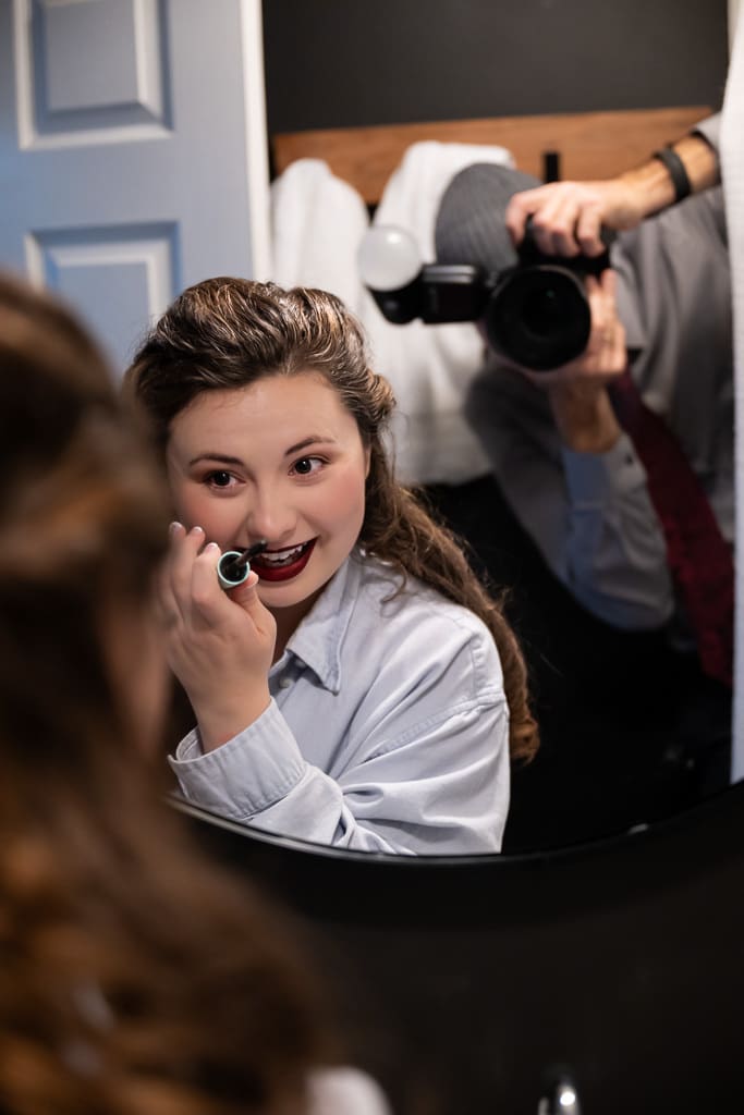 Tamieka puts on red lipstick in a mirror as Etienne of ATN Photography captures her reflection