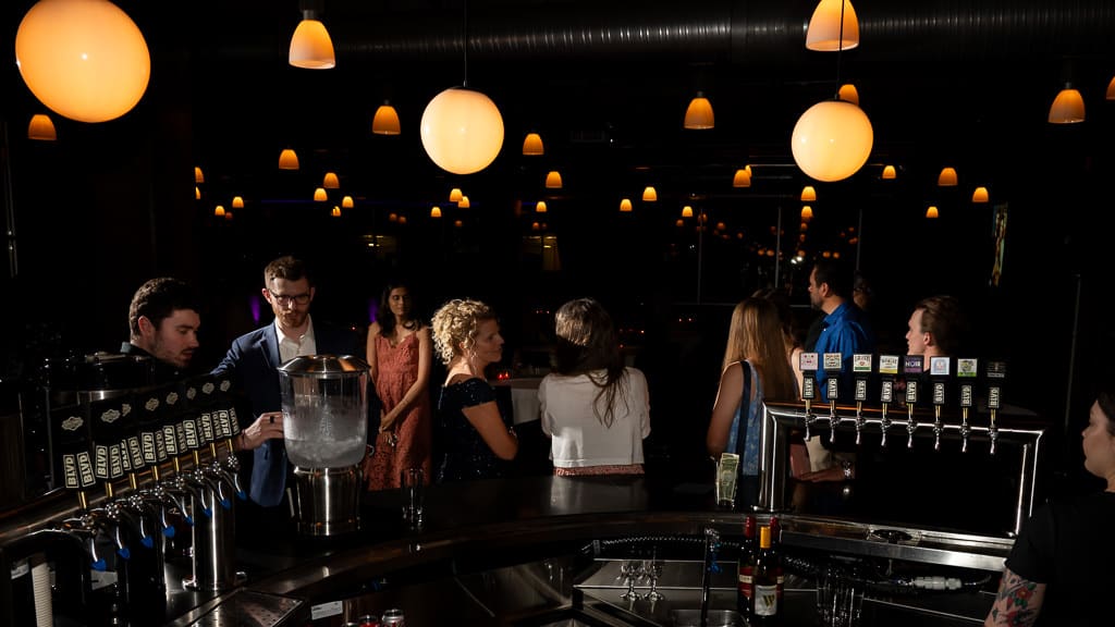 Guests gathered at the bar under glowing lights during a wedding at Boulevard Brewing Company in Kansas City