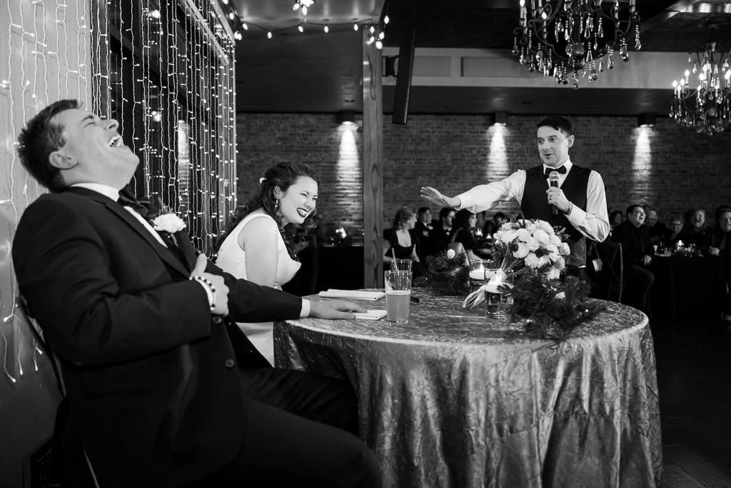 Black and white photo of Drake laughing hard at the best man's speech at The Stanley, Tamieka smiling beside him