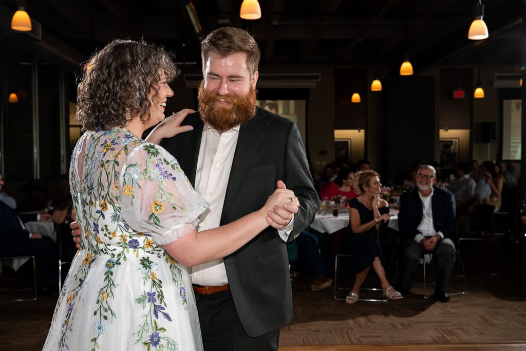 Groom laughing as he dances with the bride during their first dance