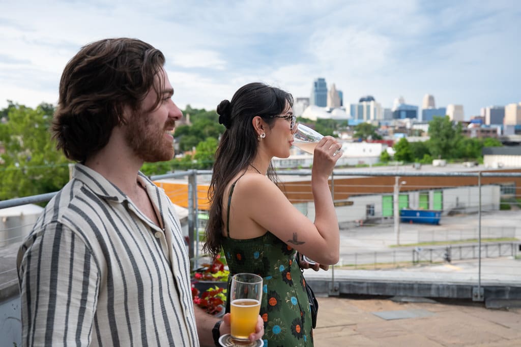 Wedding guests sharing drinks on the rooftop with a skyline view of Kansas City at Boulevard Brewing Company