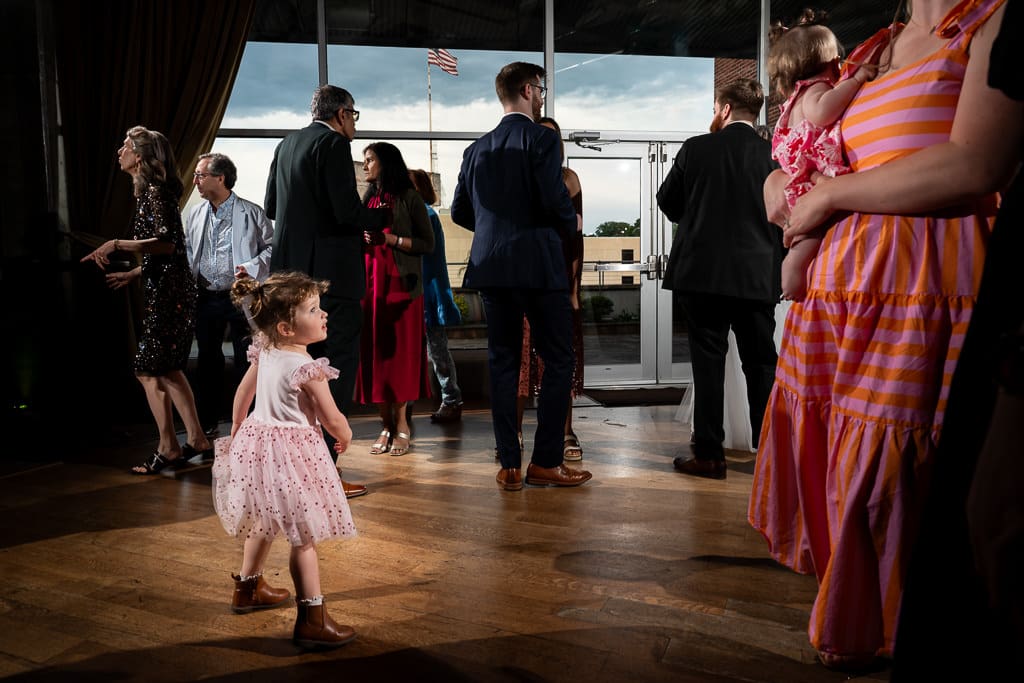 Little girl in a pink dress dancing as guests mingle at a Boulevard Brewing Company wedding reception