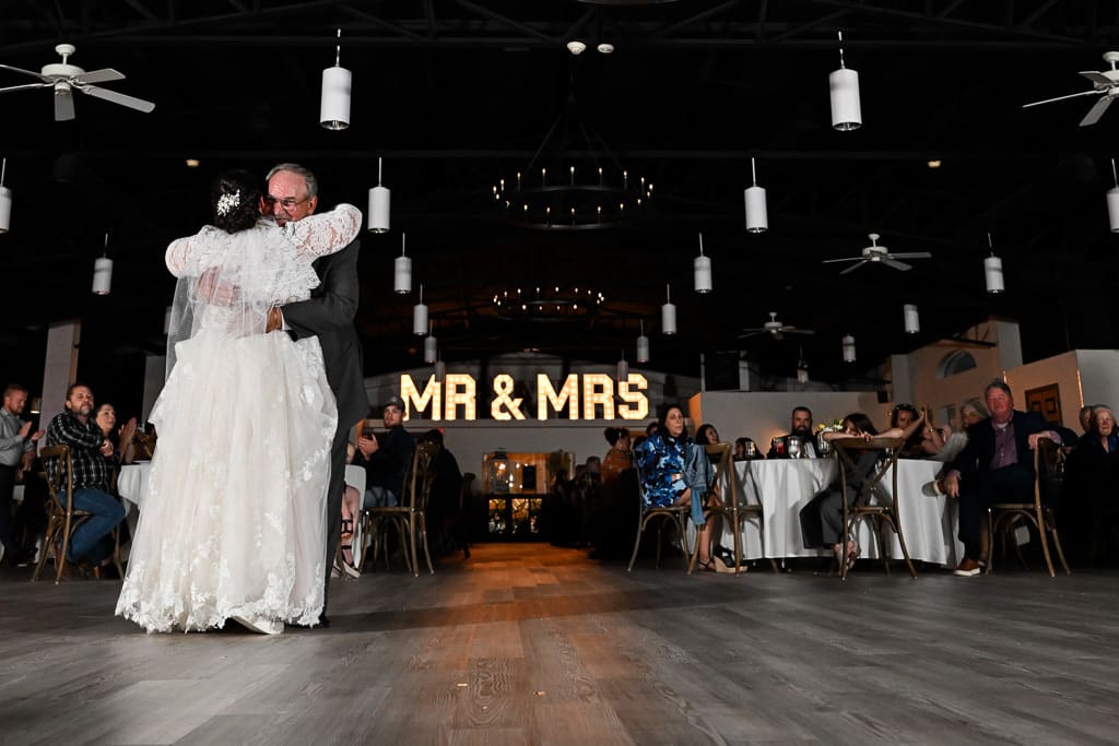 Kayleigh dances with her dad under the Mr and Mrs sign in the Lone Summit Ranch reception hall