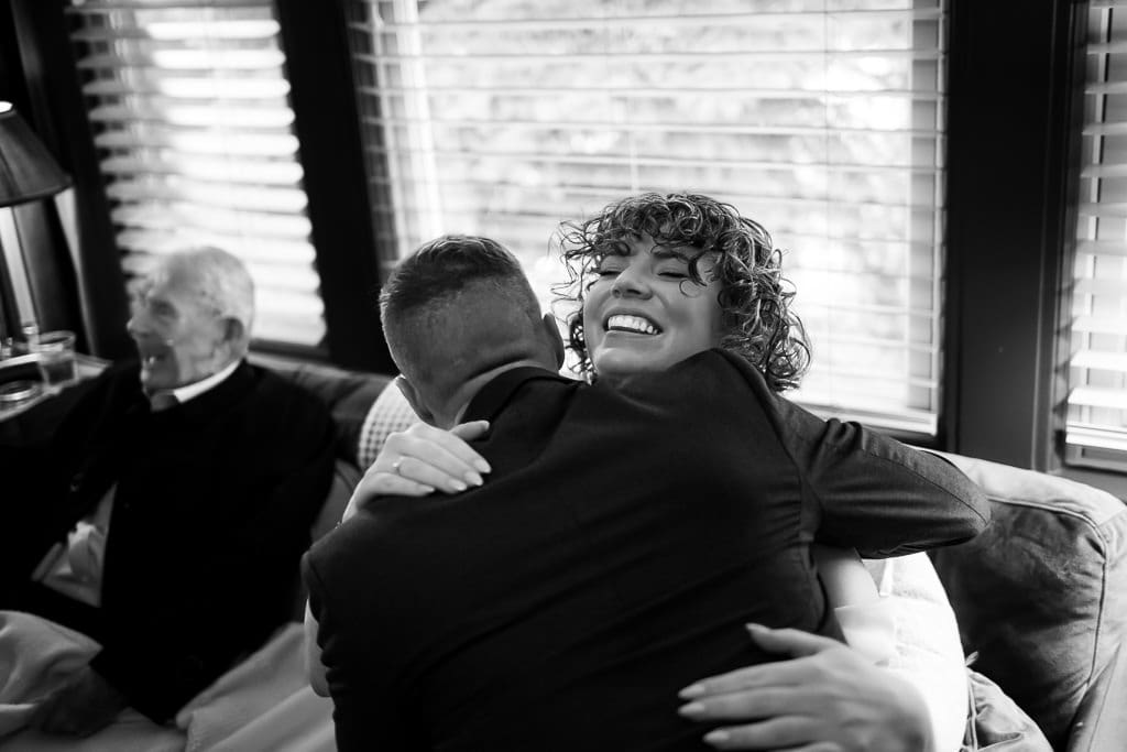Black and white photo of the bride hugging a guest with joy