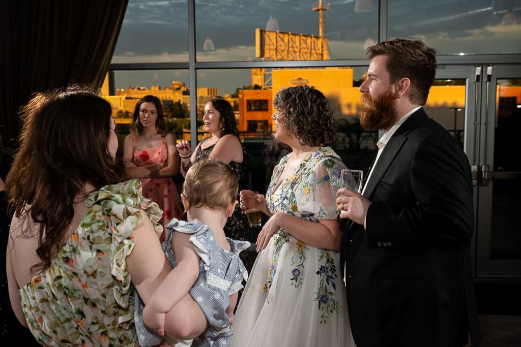 Bride and groom talking with guests in golden evening light with a skyline view of Kansas City at Boulevard Brewing Company