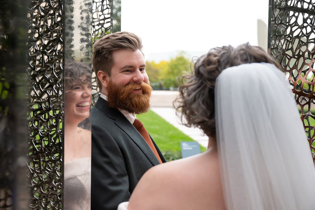 Groom smiling at the bride beside the stainless steel sculpture at the Nelson Atkins Museum of Art in Kansas City