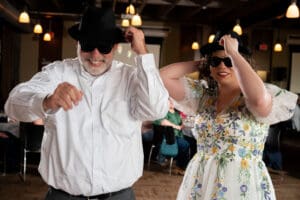 Bride and her father in matching black hats and sunglasses dancing during the father daughter dance