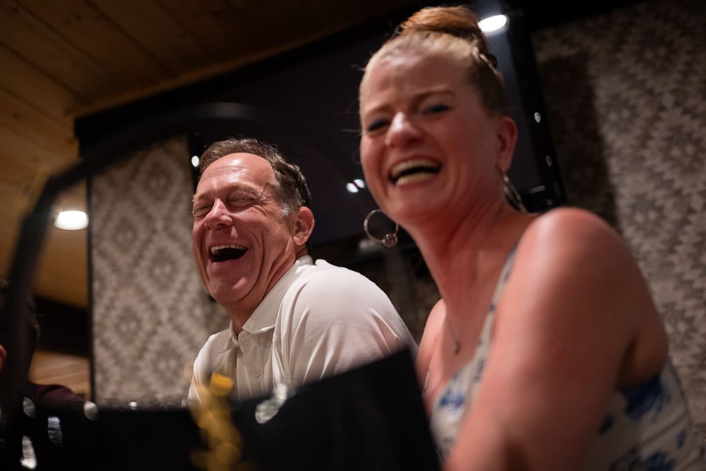 Two longtime friends laughing together at the wedding reception