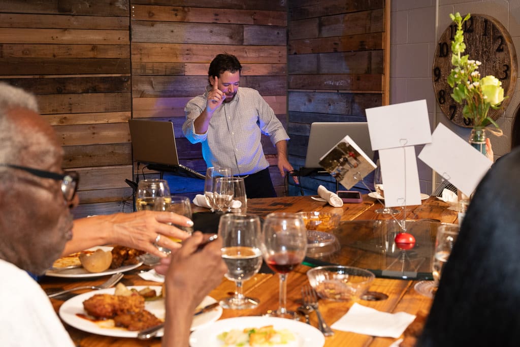 Guests sharing dinner at a long wooden table during an LGBTQ wedding reception in Kansas City