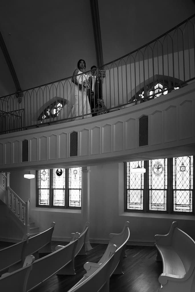 Black and white view of the Melrose Abbey chapel with stained glass windows and a person standing in the balcony