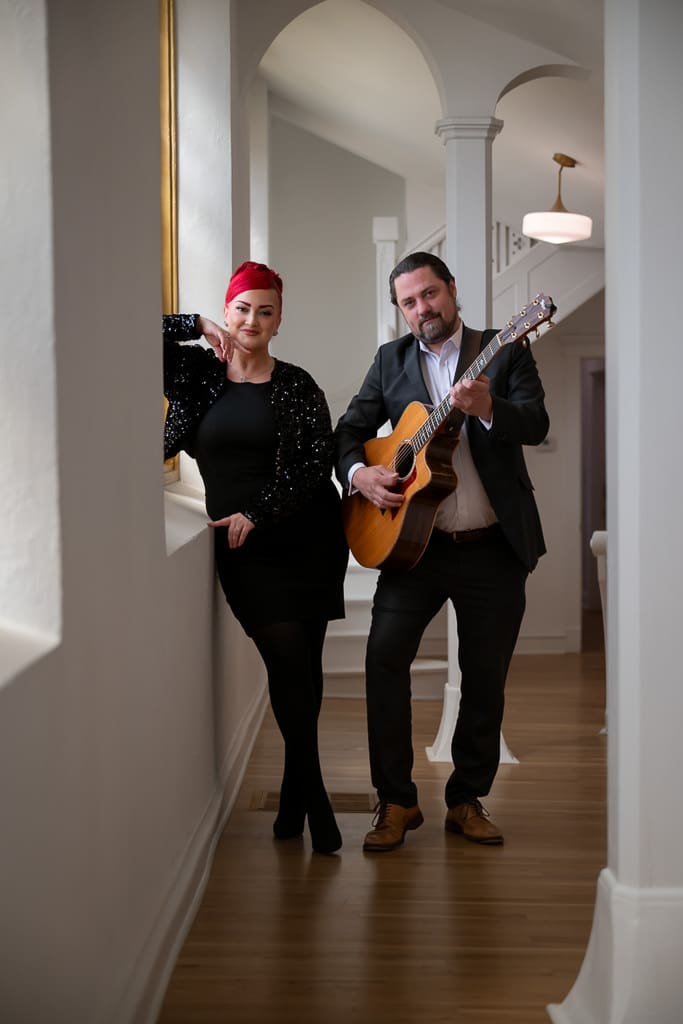 Singer and guitarist standing together in a white arched hallway at Melrose Abbey