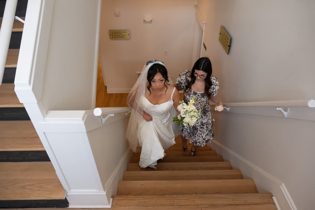Bride climbing the stairs with her bridesmaid at her side at Melrose Abbey
