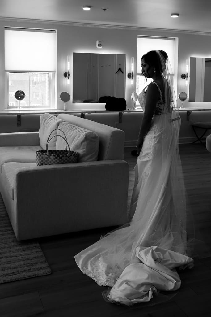 Black and white photo of a bride standing in the bridal suite at Melrose Abbey, her train spread across the floor