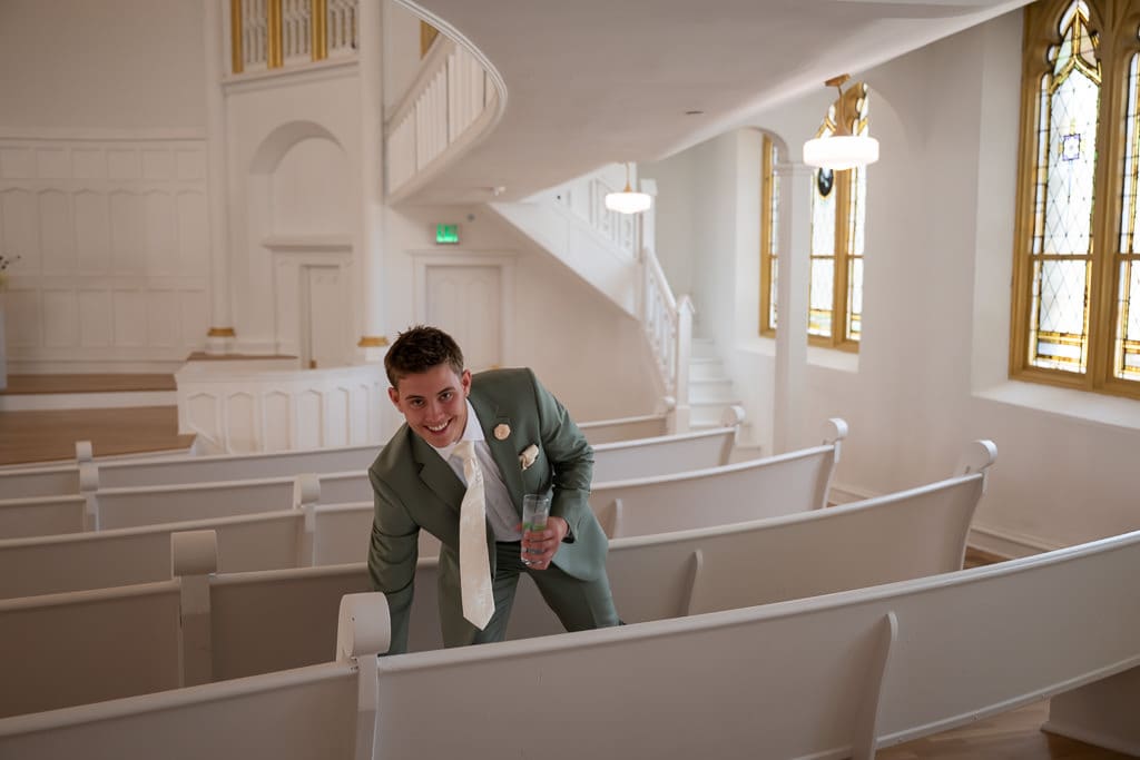 Man in a green suit smiling as he leans on a white pew in the Melrose Abbey chapel