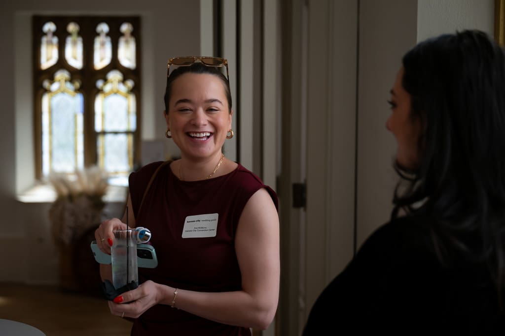 Wedding vendor laughing in front of a stained glass window at a networking event at Melrose Abbey