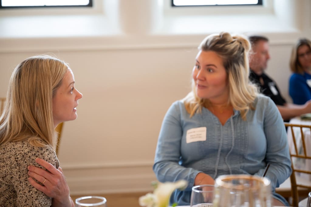 Two wedding vendors talking at a table in the Melrose Abbey ballroom
