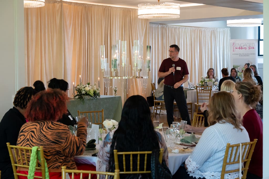 Speaker addressing wedding vendors seated at round tables in the Melrose Abbey ballroom