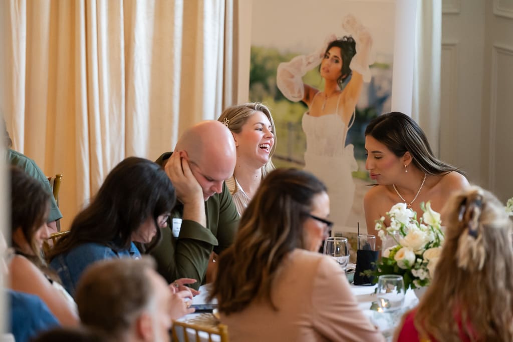 Wedding vendors laughing around a table in the Melrose Abbey ballroom, with a large painted bridal portrait behind them