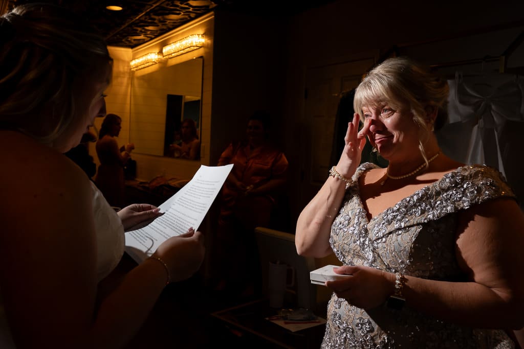 Mother of the bride wiping away tears while the bride reads her a letter