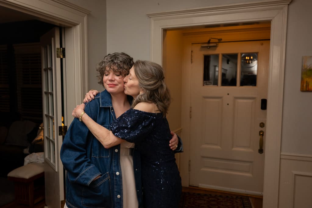 Mother kissing the bride on the cheek in the entryway