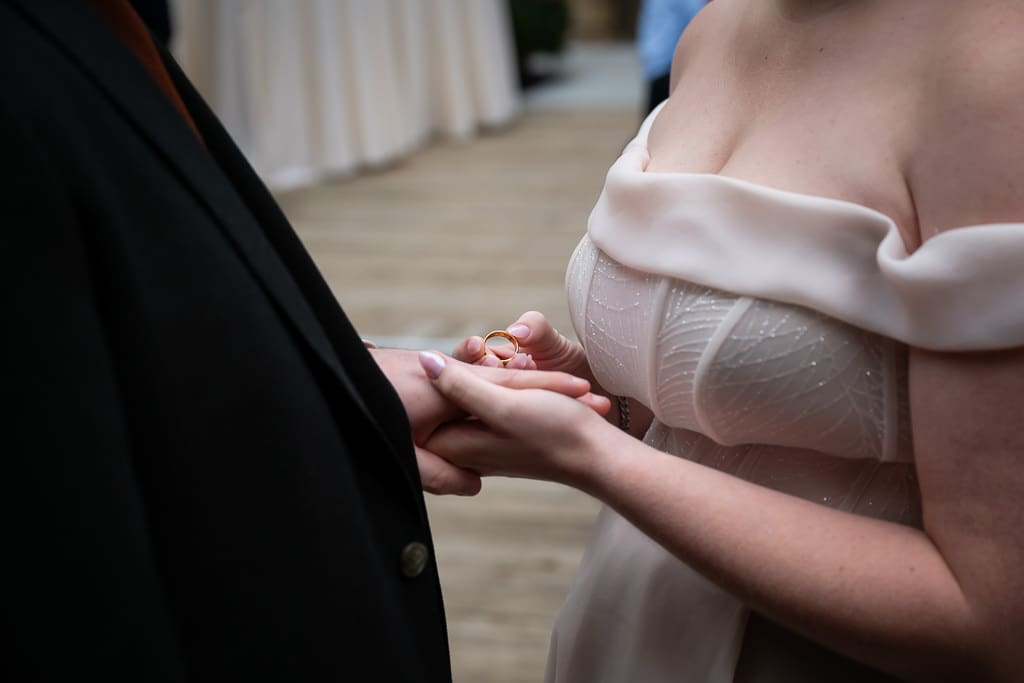 Close up of the bride about to place the ring on the groom's finger during the ceremony