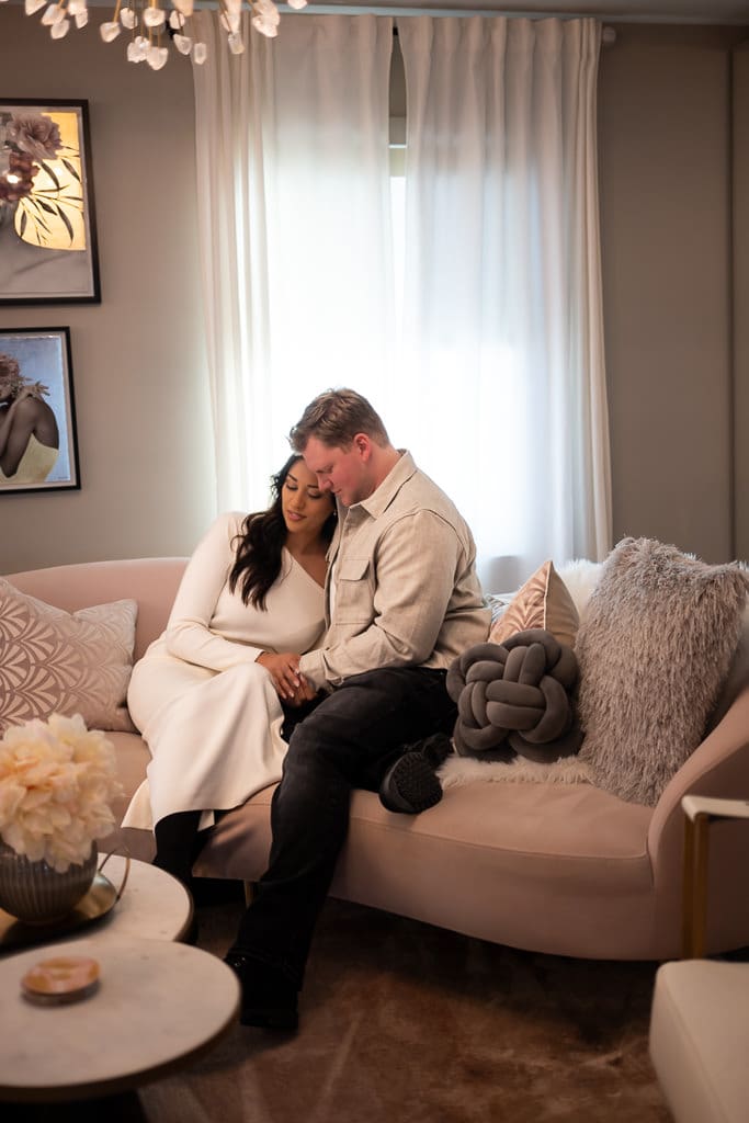 Ashley and Riley cuddle on a pink sofa in the bridal suite of The Cottage at Warren Place