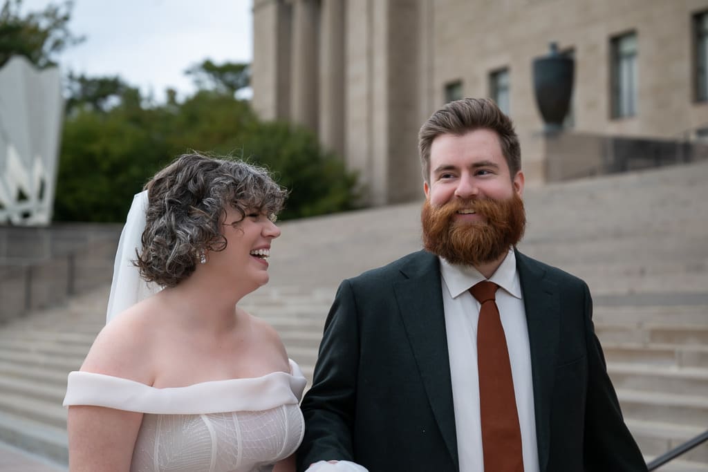 Bride laughing with the groom on the steps of the Nelson Atkins Museum of Art in Kansas City