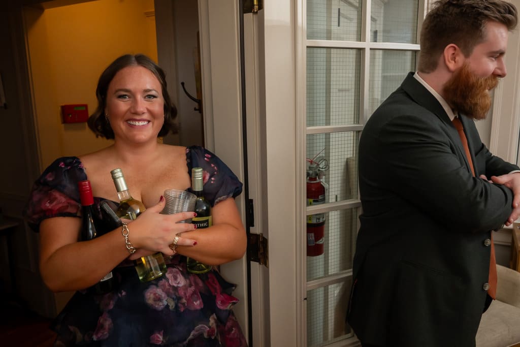 Guest carrying wine bottles into the dining room as the groom looks on at an intimate wedding at Southmoreland on the Plaza