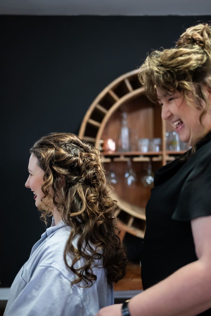Tamieka smiles at her mom, a hairdresser, as she styles her daughter's hair the morning of the wedding