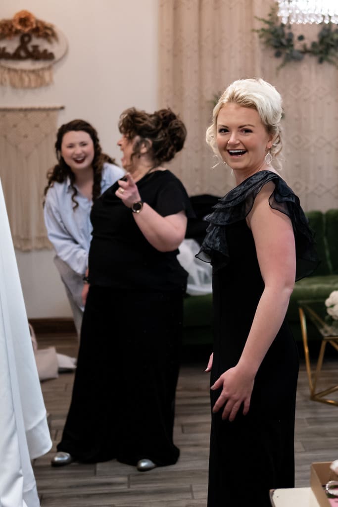 Tamieka and her mom laugh together while getting ready as a bridesmaid smiles nearby