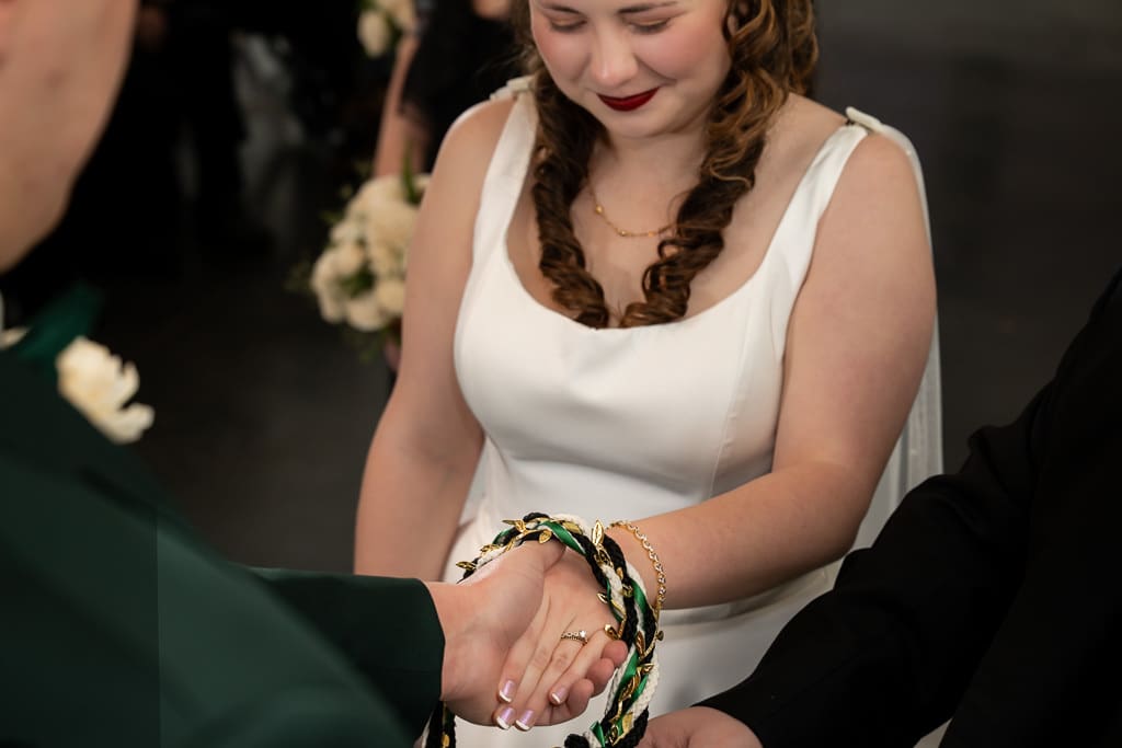 Tamieka smiles down at their hands bound with a braided cord during the handfasting